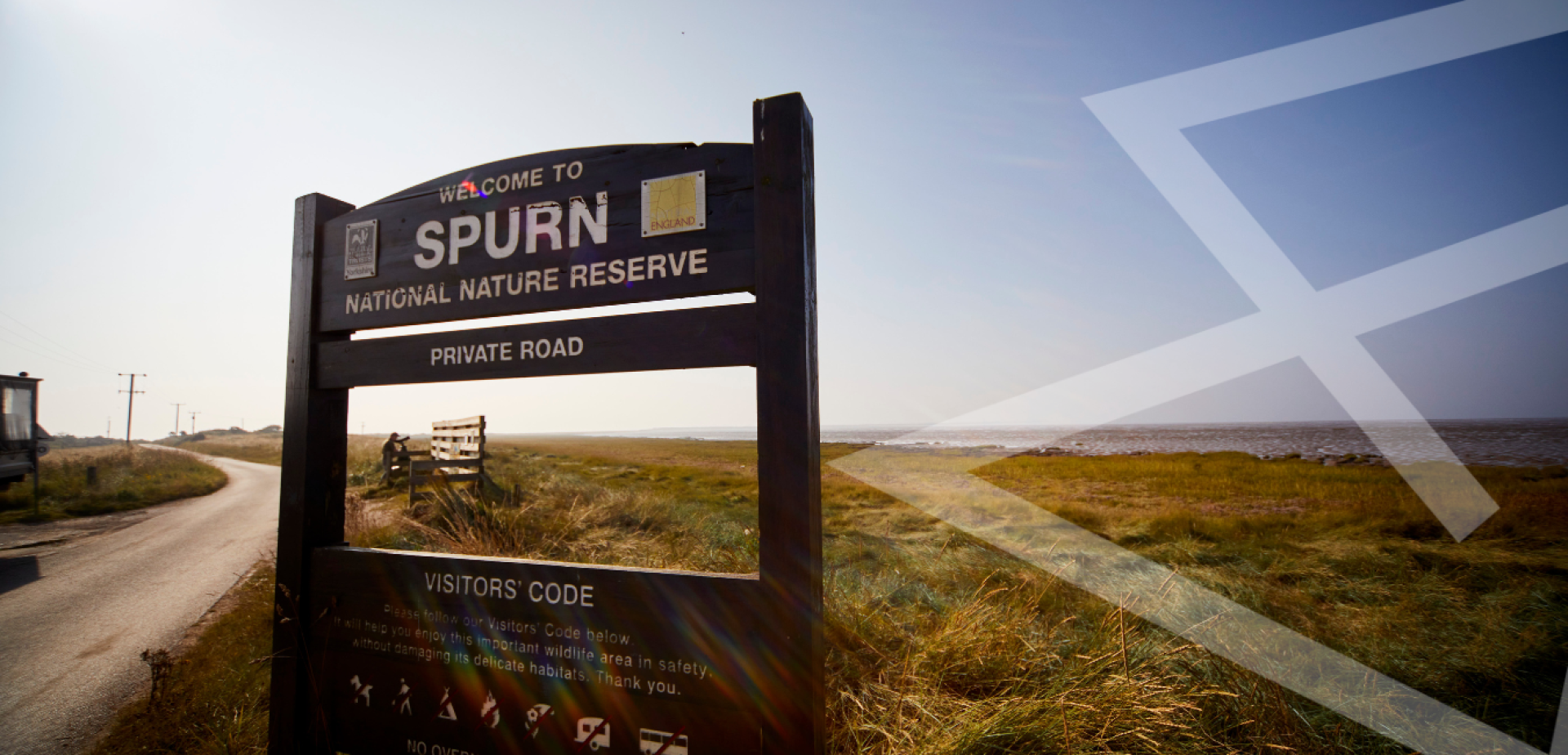 Picture of sign at the entrance to Spurn Point Nature reserve with photographer in the distance